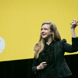 yellow background on screen with Kirryn in the foreground