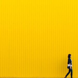 woman walking past yellow wall