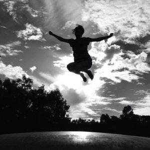Jumping on a trampoline with the clouds behind