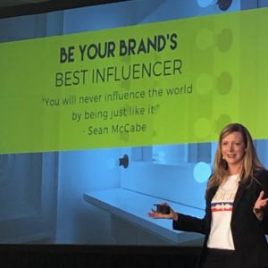 Kirryn standing in front of a screen that says BE Your Brands Best Influencer